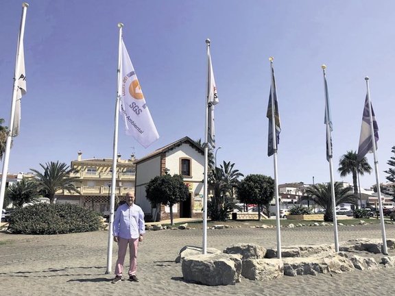 Jesús Atencia junto a la bandera de calidad de playas. Archivo