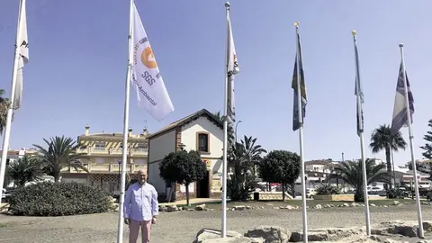 Jesús Atencia junto a la bandera de calidad de playas. Archivo
